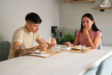 Two young hispanic people eating traditional arepas in the living room.