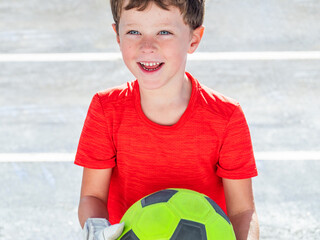 adorable elementary boy with goalkeeper gloves and soccer ball in hand
