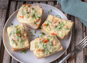 Open faced grilled ham and cheese sandwich with bell peppers and chives on french baguette
