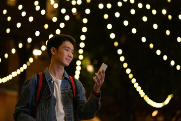 Portrait of hipster man standing in city avenue with blurred night street lights background