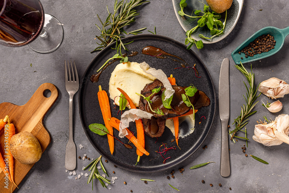 Wall mural Beef cheeks in wine-honey sauce served with mashed potatoes and
caramelized carrots in rosemary and honey