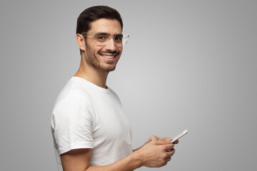 Side portrait of man on gray background in transparent safety glasses, holding tablet pc in hands - obrazy, fototapety, plakaty