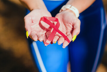 AIDS awareness.Caucasian woman hold red ribbon.Blurred background.World AIDS day concept.