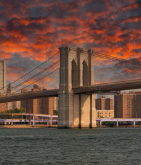 Obraz premium Span of the Brooklyn Bridge against the backdrop of the skyscrapers of Manhattan under a bright sky with clouds