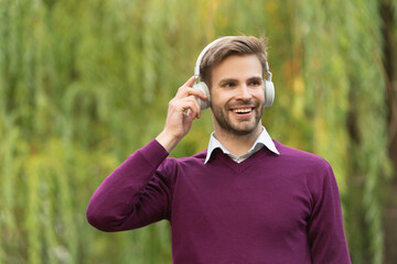 cheerful young handsome man listen music in headphones outdoor