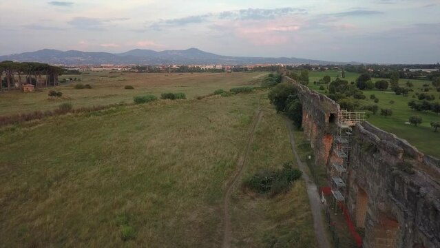 Low angle sun lights arches in ancient Roman aqueduct ruin in Rome