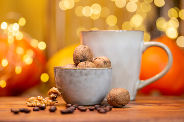 Big cup of coffee and bowl filled with walnuts on wooden table with pumpkins in autumn 