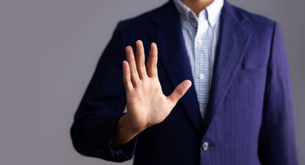 Obraz premium Young asian businessman in dark blue jacket posing hand touching on gray background.