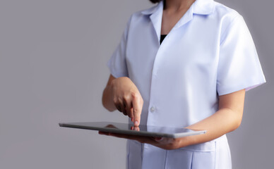 Female doctor in white safari finger pointing and touching on tablet screen grey background.