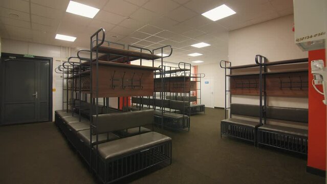 Empty locker room with hooks and shelves with soft benches in school building. Dressing room for athletic center visitors