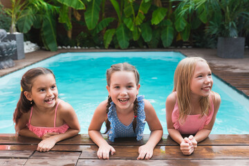 Portrait of girls friends having fun in outdoor swimming pool. Kids playing in pool together....