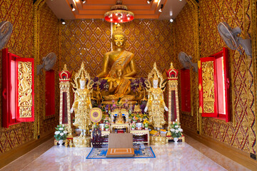 Ancient golden buddha statue in antique ubosot for thai people travelers travel visit and respect praying blessing to holy mystery worship at Wat Maniwong or Mani Wong temple in Nakhon Nayok, Thailand