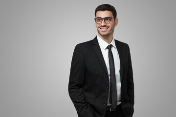 Businessman in black suit and glasses looking aside with smile, feeling full of ideas and ambitions