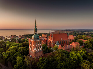 Great view of the beautiful city of Frombork located in Warmia, Poland. Cathedral Hill among trees at sunset.