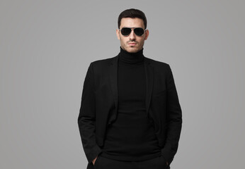 Obraz premium Guy in total black with turtleneck, sunglasses and jacket, looking serious, suspicious and reserved