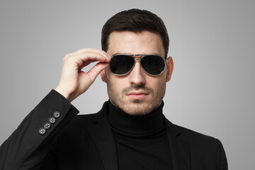 Close up of bodyguard or secret agent wearing suit and sunglasses, isolated on grey background