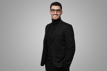 Contemporary intelligent business man wearing black suit standing against grey