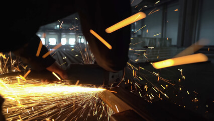 Professional male worker cutting metal with a grinding machine