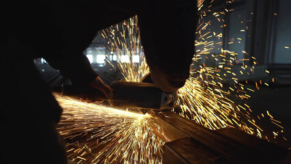 Professional male worker cutting metal with a grinding machine