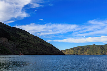 The headlands at the entrance to Akaroa Harbour, South Island, New Zealand. A sailboat is just visible to the left