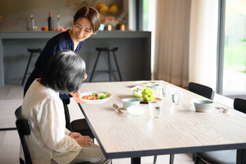 Woman serving food to grandmother in dining room