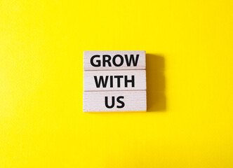 Grow with us symbol. Wooden blocks with words Grow with us. Beautiful yellow background. Business and Grow with us concept. Copy space.
