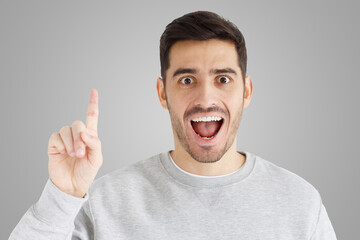 Portrait of excited man looking at camera, smiling, pointing finger up if he has great idea