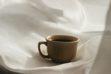 cup of coffee in the morning. espresso coffee. Coffee porridge on a white background
a cup of coffee on a white cloth. sun rays on a cup of coffee