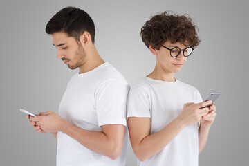 Unhappy couple ignoring each other using mobile phones, isolated on gray