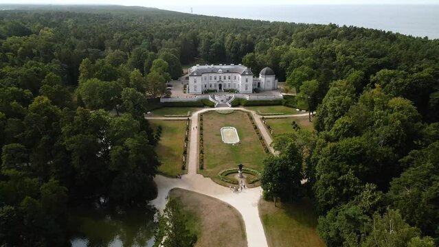 Aerial slow movement around Tiskeviciai Palace surrounded by dense trees in Palanga