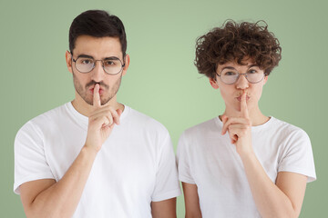 Young couple showing shh gesture on green background