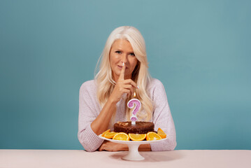 Beautiful woman celebrating her birthday sitting over a blue background 
