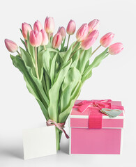 Fototapeta premium Lovely tulips bunch with pink gift box and blank greeting card at white background