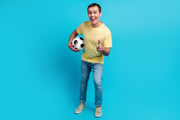 Fototapeta na wymiar Soccer player man fan with ball pointing you hand gesture isolated on blue color background