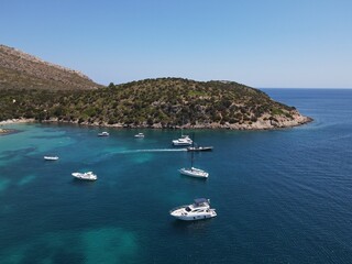 Aerial view of Cala Moresca and Figarolo Island in Golfo Aranci, north Sardinia. Birds eye from above of yacht, boats, crystalline and turquoise water. Tavolara Island in the background, Sardegna.