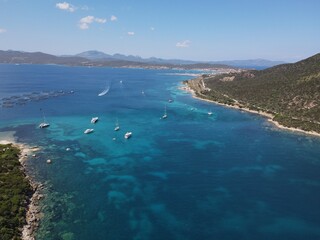 Fototapeta na wymiar Aerial view of Cala Moresca and Figarolo Island in Golfo Aranci, north Sardinia. Birds eye from above of yacht, boats, crystalline and turquoise water. Tavolara Island in the background, Sardegna.