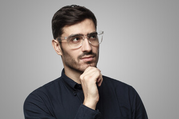 Fototapeta premium Portrait of pensive businessman holding hand on chin, looking up