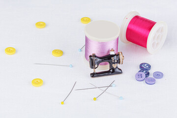 still life of a skein of thread for sewing, needles, buttons, sewing machine on a white background