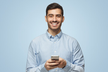 Portrait of positive business man laughing out loud while using mobile phone on blue background