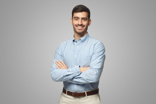 Handsome business man in blue shirt standing with crossed arms on gray background