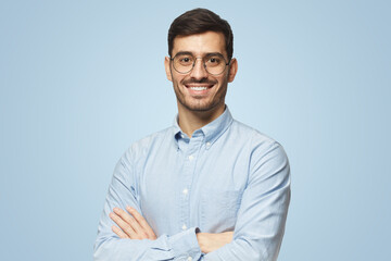 Modern businessman in shirt standing with crossed arms, isolated on blue background