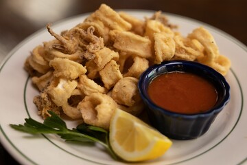 Plate of crispy squid with lemon and red sauce
