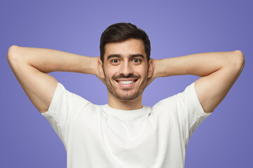 Fototapeta na wymiar Man standing isolated on purple background with arms behind head, relaxing in free time