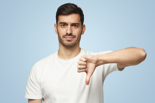 Man showing thumb down or dislike, isolated on blue background
