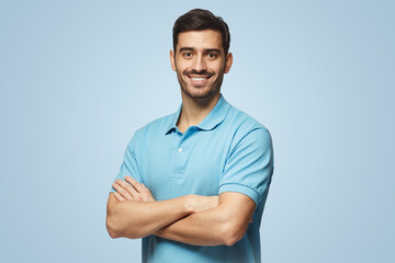 Portrait of young european man on blue background in polo shirt with crossed arms smiling at camera