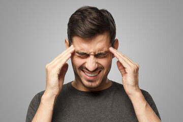Man isolated on gray background, showing how much his head hurts, experiencing pain