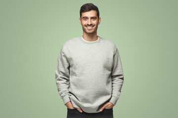 Young handsome man in gray sweatshirt isolated on green background