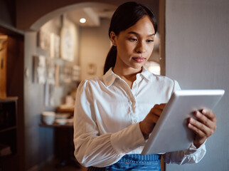 Cafe startup, digital tablet and entrepreneur checking restaurant website online on internet. Small business owner, modern cafeteria and woman leader from mexico planning food menu on mobile device. © Siphosethu F/peopleimages.com