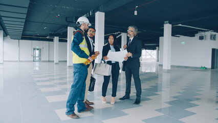 portrait of business team talking about maintenance of industrial building with glass walls and spacious halls. People and talks concept. - 535767397