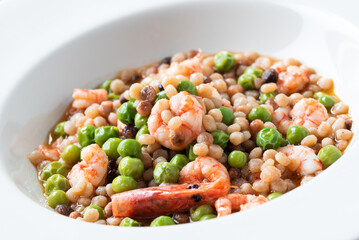 Piatto di deliziosa zuppa di fregula sarda con gamberetti e pisellini primavera, cibo italiano 